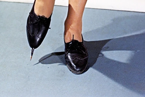 A woman wearing black shoes with daggers on the soles.