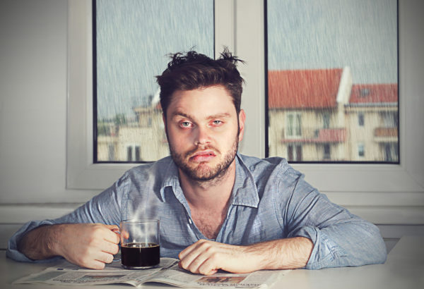 An exhausted man drinking coffee the morning of Daylight Saving Time