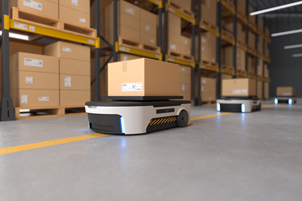 A robot worker hauls a box through a warehouse