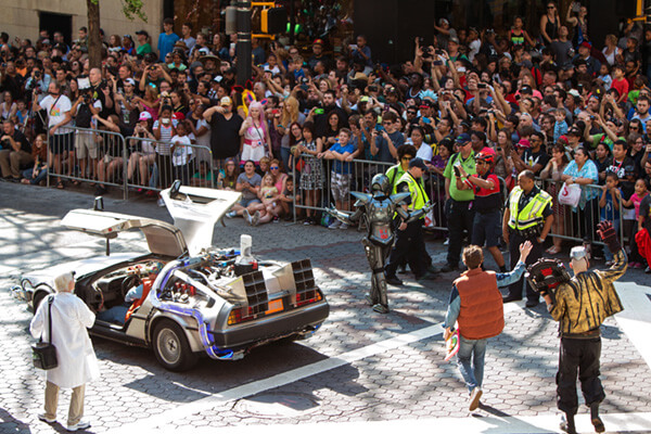 Actors portraying Marty and Doc approaching a DeLorean in front of a crowd
