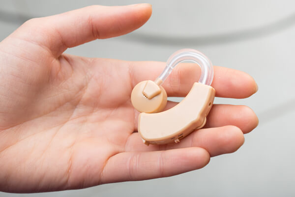 A hearing aid sitting in someone's hand.