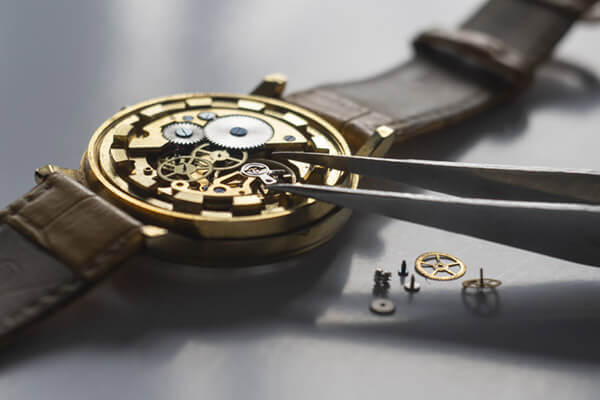 A mechanical watch being repaired with tweezers